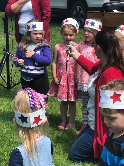 students wearing red white and blue talk into a microphone